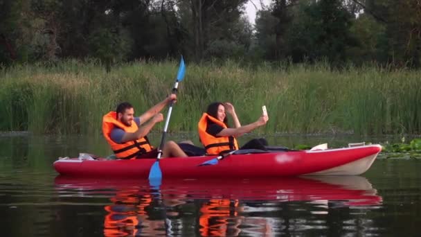 Chica hace selfie en un kayak, el tipo muestra los pulgares hacia arriba. Movimiento lento — Vídeos de Stock