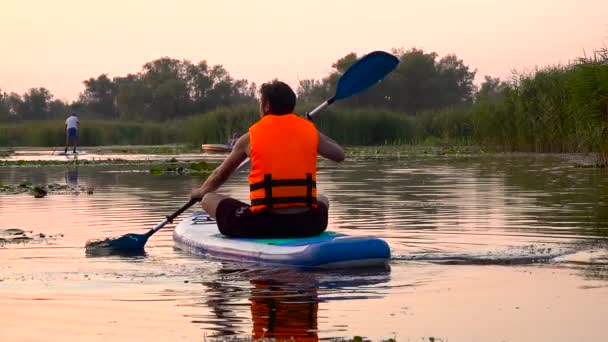 Mann paddelt auf aufblasbarem Floß hinaus. Zeitlupe — Stockvideo