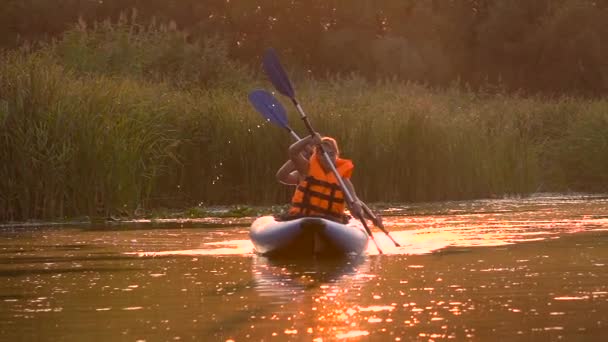 在日落时 皮划艇上的一对人漂浮在平静的河上 慢动作 — 图库视频影像