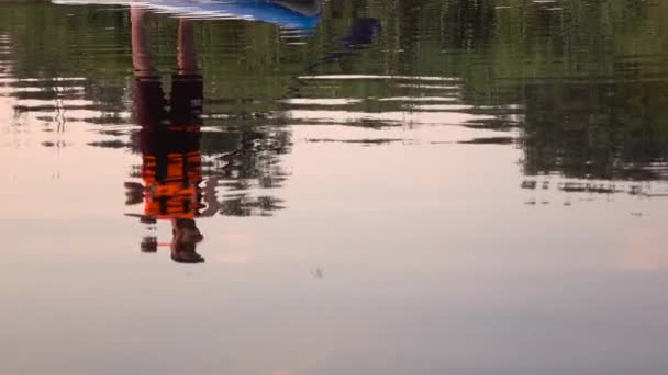 Reflection of a guy in the water who rows in an inflatable raft. Slow motion — Stock Video