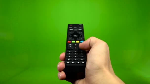 Male hand operating a tv remote control on a green screen — Stock Video