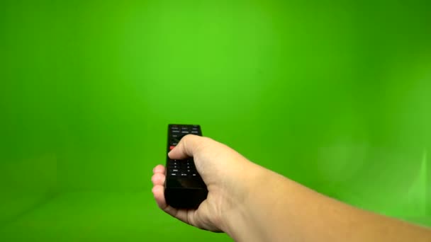 Vrouwelijke hand die van een afstandsbediening van de tv op een groen scherm — Stockvideo