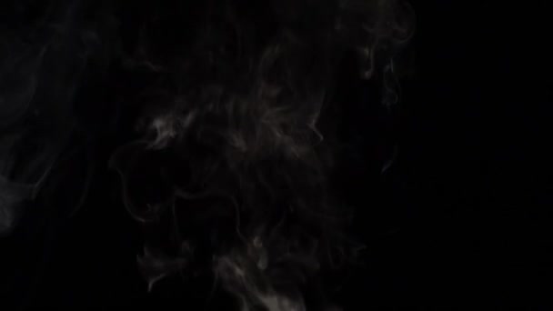 Rokerige wolken boven een zwarte achtergrond. Slow motion — Stockvideo