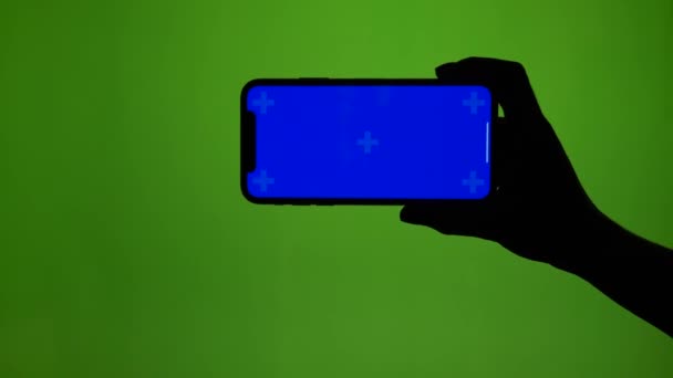 Girlish hand holds horizontally smart phone on green screen — Stock Video