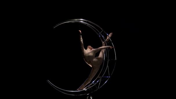 体操运动员在垂直的绳子上在金属结构的月亮上旋转。黑色背景 — 图库视频影像