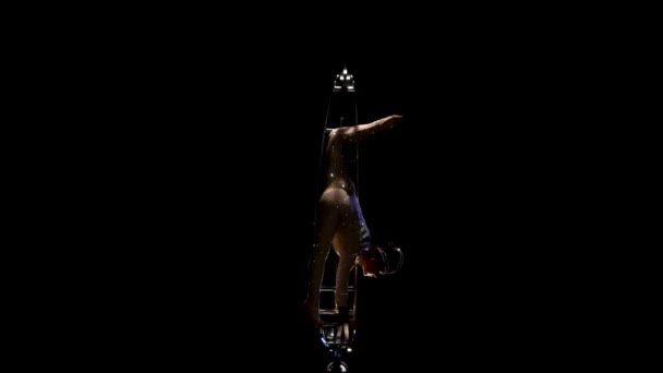 El movimiento acrobático sobre la estructura giratoria en forma de la gimnasta del mes cumple los trucos. Fondo negro — Vídeo de stock