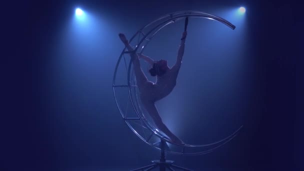 体操运动员在垂直的绳子上在金属结构的月亮上旋转。蓝色烟背景 — 图库视频影像