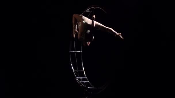 Гимнастка в блестящем костюме выполняет трюки на специальном дизайнерском спутнике. Чёрный фон — стоковое видео