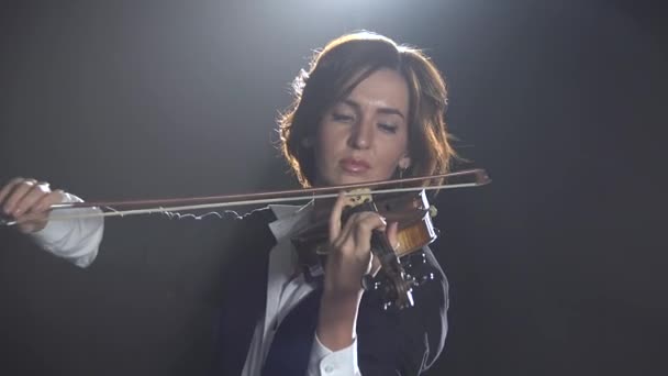 Mädchen spielt die klassische Komposition einer Geige in einem schwarzen Rauchstudio — Stockvideo