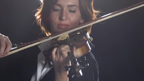 Mulher toca a composição de violino um estúdio de fumaça preta — Vídeo de Stock