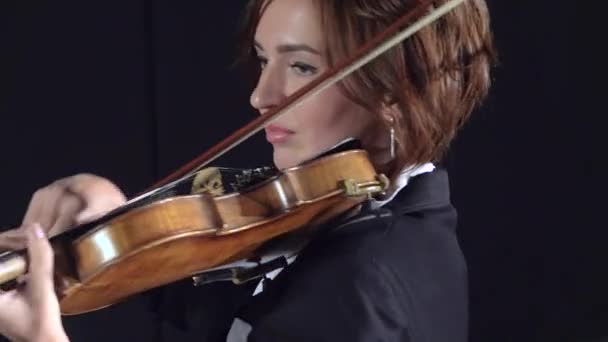 Las muchachas tocan los violines en la composición en la habitación. Fondo negro. De cerca. — Vídeos de Stock