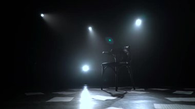 Sandalye fenerler dağınık kat sayfalardaki ile karanlık bir stüdyo ortasında duruyor. Siyah duman arka plan