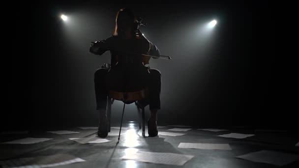 Девушка Играет Виолончели Темной Комнате Фонариками Листы Нот Разбросаны Полу — стоковое видео