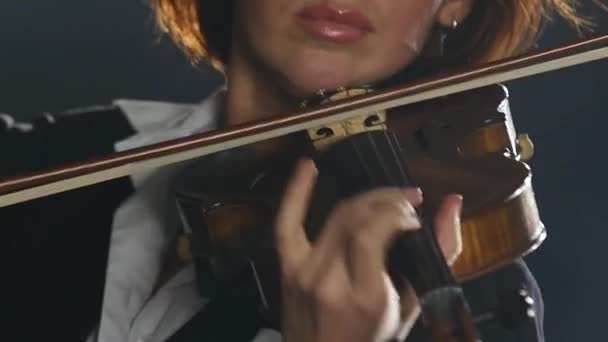 La muchacha toca el violín por la composición en la habitación oscura humeante. De cerca. — Vídeo de stock