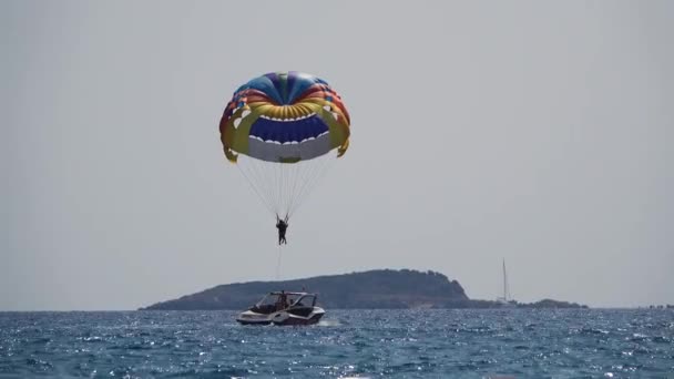 Parasailing behind a boat people flies over the sea on a parachute — Stock Video