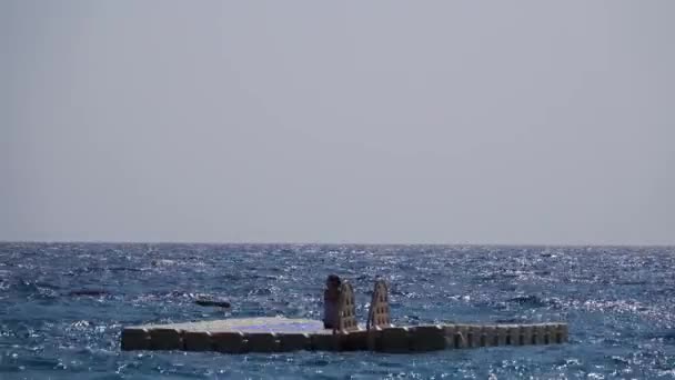 Chica se sienta en una balsa en medio del mar abierto — Vídeos de Stock