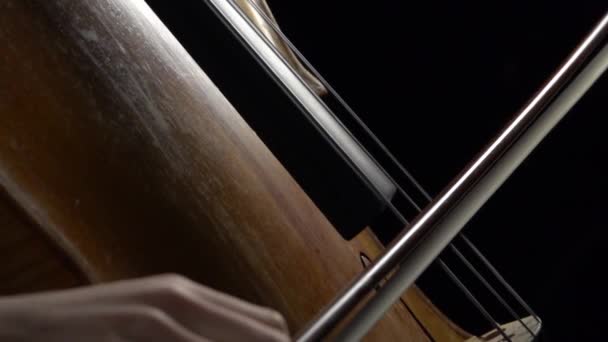 Violoncelle près des arcs portent sur la corde avec des notes dans une pièce sombre. Vue latérale. Mouvement lent — Video