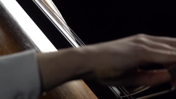 Handen gaan over de snaren van de cello in de achtergrond vellen met notities. Close-up. Zijaanzicht. Slow motion — Stockvideo