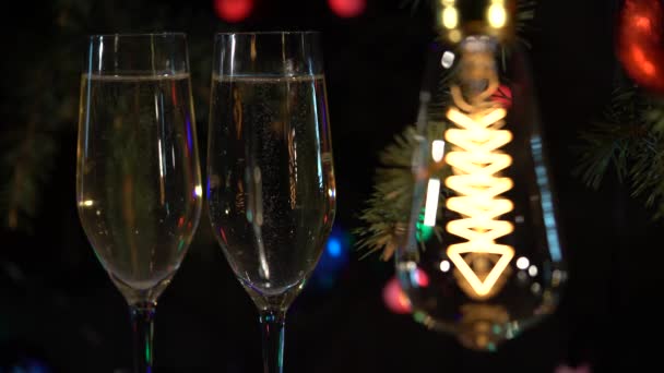 2 つのグラスをテーブルの上のシャンパンは、お祭りの雰囲気のガーランドに電球が点灯しています。 — ストック動画