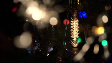 Bir Noel ağacı fonunda havai fişekleri ve bir ampul yanıyor. Yakın çekim. Ağır çekim