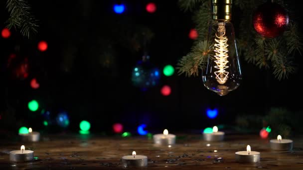 Árbol de Navidad y juguetes en la mesa son velas en la parte delantera del plan, la bombilla se enciende y apaga — Vídeo de stock