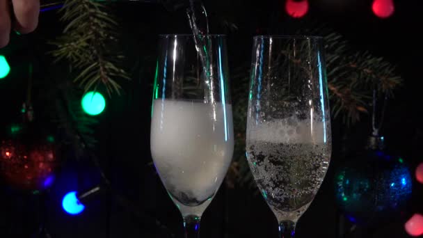 Hand schenkt vor dem Hintergrund der Neujahrsstimmung ein Glas Champagner ein. Zeitlupe. Nahaufnahme — Stockvideo