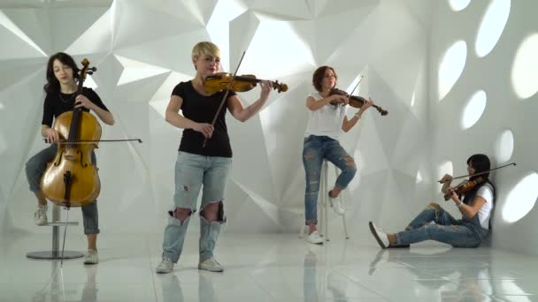 Muzikale strijkkwartet meisjes voert de samenstelling op drie violen en cello. Witte studio — Stockvideo