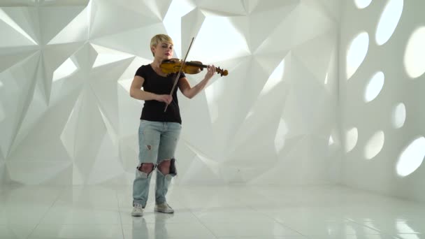 Violinista interpreta una composición musical sobre un violín en un estudio blanco — Vídeos de Stock