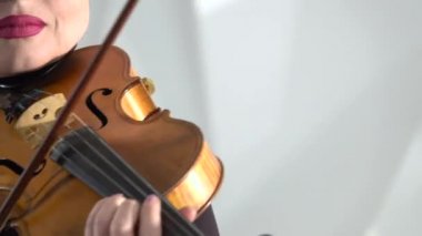 Kız ona selam dizeleri üzerinde oynarken bir keman tutar. Yakın çekim. Beyaz arka plan