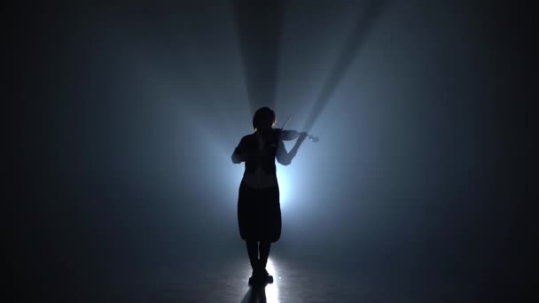 Девушка играет на скрипке классическую композицию в темно-дымчатой комнате. Силуэт. Чёрный дым — стоковое видео