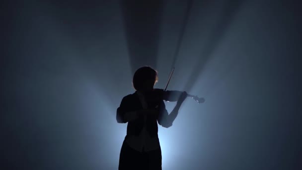 Violinista se apresenta em um violino em um estúdio de fumaça preta. Silhueta. Preto fumaça fundo — Vídeo de Stock