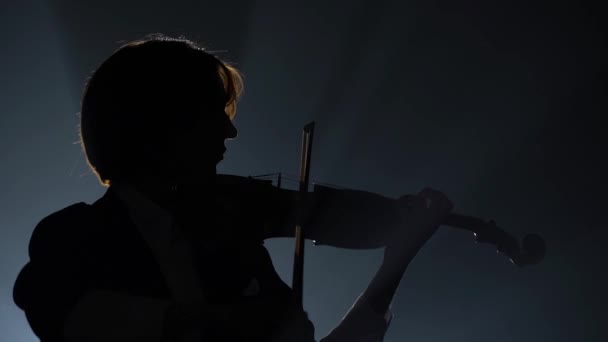 Violinista actuando en un estudio oscuro con una linterna. Fondo negro. Silueta — Vídeos de Stock