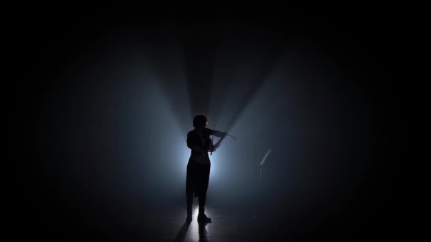 Γυναίκα παίζει βιολί και φαίνεται στο περίπτερο μουσική στο σκοτάδι. Σιλουέτα. Μαύρος καπνός φόντο — Αρχείο Βίντεο