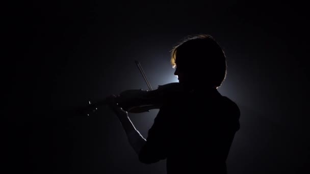 La música regresa a la cámara tocando el violín. Fondo de humo negro. Vista trasera — Vídeos de Stock