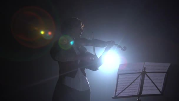 Il violinista guarda le note e suona. Silhouette. Nero sfondo fumo — Video Stock