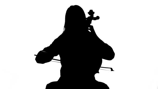 La mujer toca la música de violonchelo en un estudio blanco. Fondo blanco.Silhouette. fondo blanco. Movimiento lento — Vídeo de stock