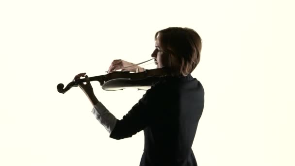 Chica actúa en un violín en un estudio blanco. Fondo blanco. Movimiento lento — Vídeo de stock