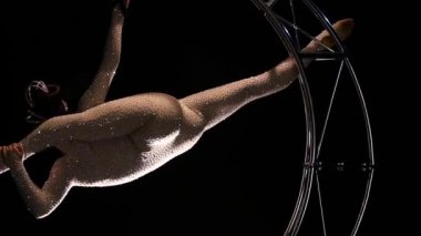 Acrobat zarif üzerinde dönen bir tasarım bir ay şeklinde bükülmüş bir kostüm. Siyah arka plan. Ağır çekim