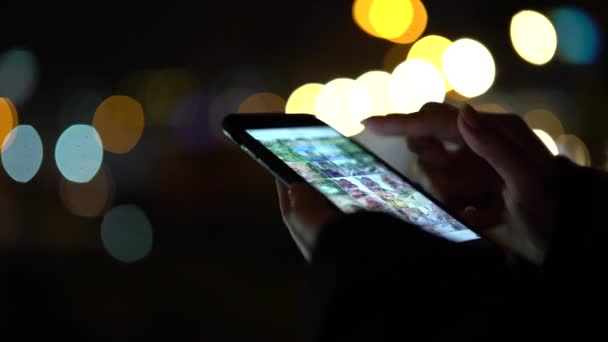 女人手里拿着一部智能手机, 五颜六色的灯光背景。特写 — 图库视频影像
