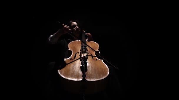 Girl in a dark room plays a cello rehearsing a composition. Black background. Bottom view — Stock Video