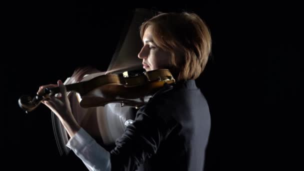 Violinist a musical composition on a violin in a black studio. Black background — Stock Video