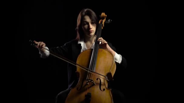 Una donna suona il violoncello in uno studio buio. Fondo nero — Video Stock