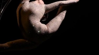 Acrobat zarif üzerinde dönen bir tasarım bir ay şeklinde bükülmüş bir kostüm. Siyah arka plan. Ağır çekim. Yakın çekim