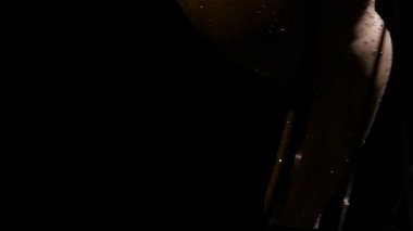 Acrobat bir metal bir yapı içinde dikey bir dize döndürür. Siyah arka plan. Ağır çekim. Yakın çekim