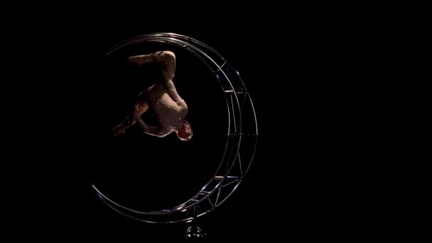 Acrobatische hangt ondersteboven in een touw aan een draaiende maan. Zwarte achtergrond. Slow motion — Stockvideo