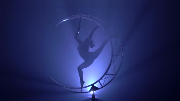 Gymnaste en costume effectue des tours dans une pièce sombre. Fond de fumée bleue. Mouvement lent.Silhouette 