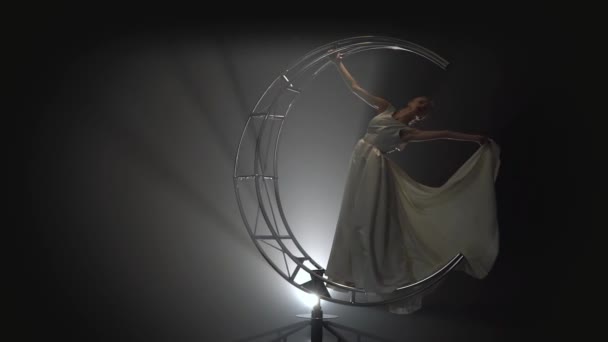 Acrobat flicka i en vit klänning bruden utför på en roterande design. Rök bakgrund. Slow motion — Stockvideo