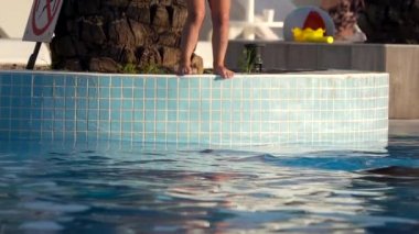 Mutlu bir çocuk havuza atlıyor. Ağır çekim