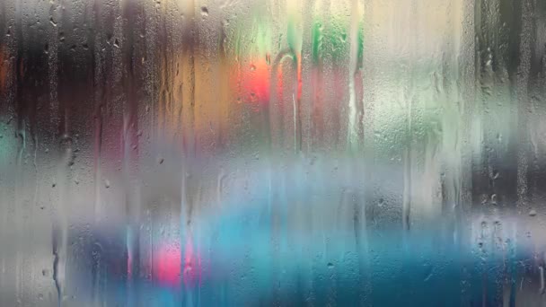 Городская улица с размытыми объектами и капельками дождя на оконном стекле — стоковое видео