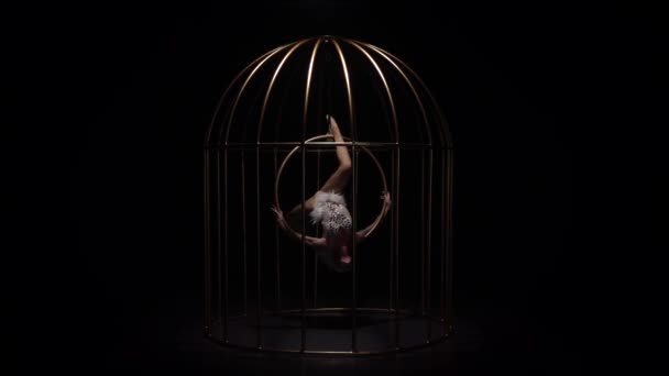 Gymnast en snurrar på en hoop i en guld bur. Svart bakgrund. Slow motion — Stockvideo